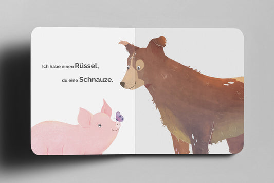 Doppelseite eines veganen Kinderbuchs zeigt ein rosa Schwein mit einem Schmetterling auf seinem Rüssel und einen braunen Hund auf weißem hintergrund, der es ansieht. Der Text darauf lautet: Ich habe einen Rüssel, du eine Schnauze.
