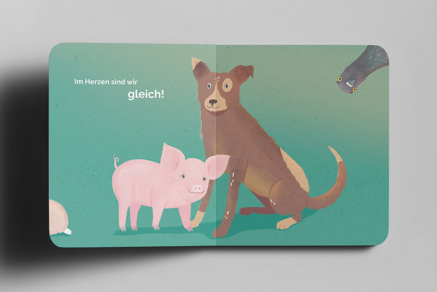 Kinderbuch-Doppelseite mit einer Illustration eines rosa Schweinchens und eines braunen Hundes auf grünem Hintergrund. Beide stehen eng beieinander und blicken freundlich nach vorn. Oben links steht der Text „Im Herzen sind wir gleich!“. In der oberen rechten Ecke lugt eine neugierige Taube mit großen Augen ins Bild.