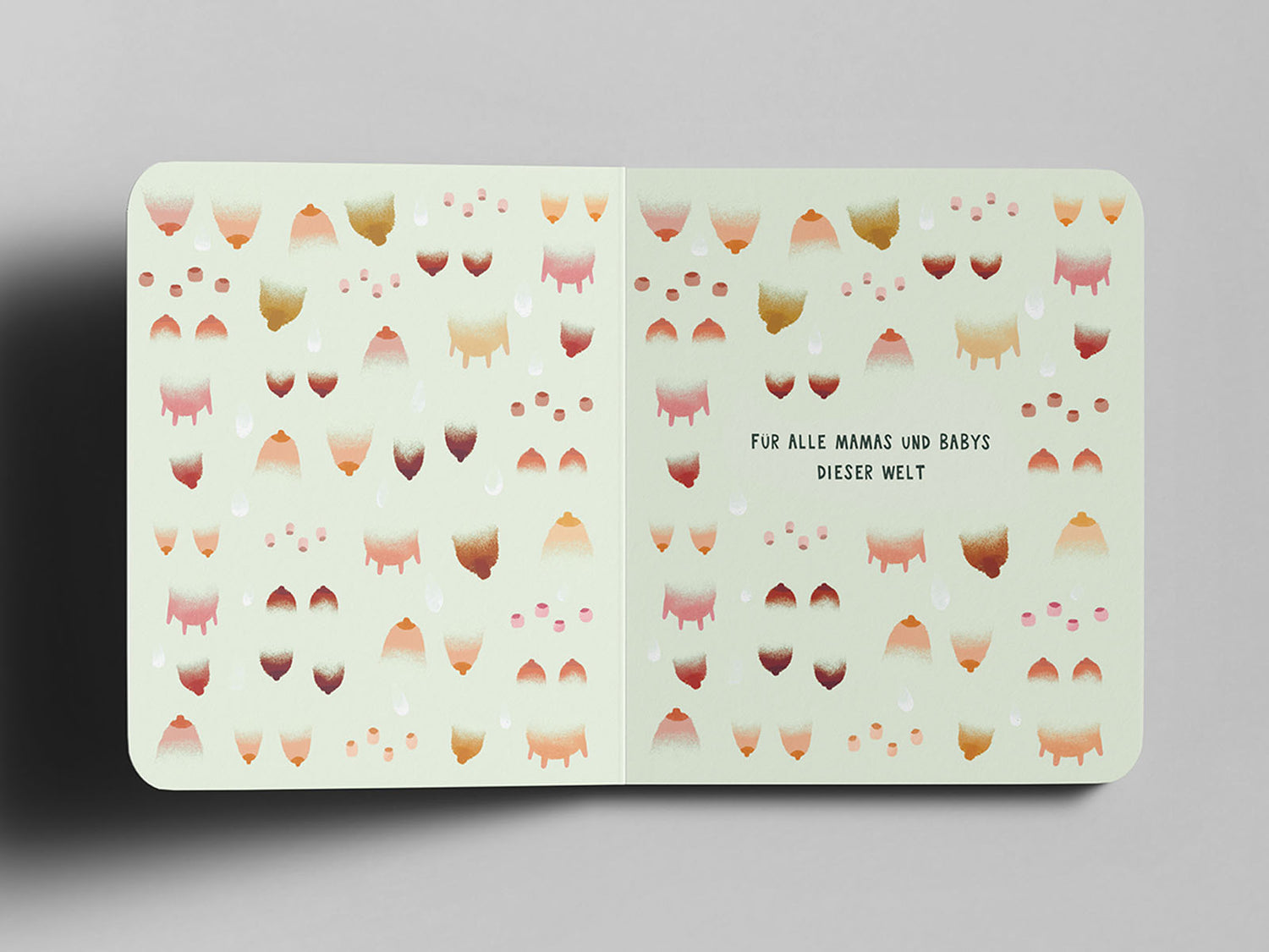 Aufgeschlagenes Pappbuch mit pastellgrünem Hintergrund. Das Muster zeigt stilisierte Tier-Euter, Zitzen und menschliche Brüste  in verschiedenen Brauntönen und Rosa-Schattierungen. In der Mitte steht in schwarzer Schrift: ‚Für alle Mamas und Babys dieser Welt‘.“