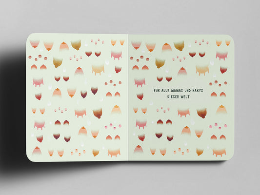 Aufgeschlagenes Pappbuch mit pastellgrünem Hintergrund. Das Muster zeigt stilisierte Tier-Euter, Zitzen und menschliche Brüste in verschiedenen Brauntönen und Rosa-Schattierungen. In der Mitte steht in schwarzer Schrift: ‚Für alle Mamas und Babys dieser Welt‘.“