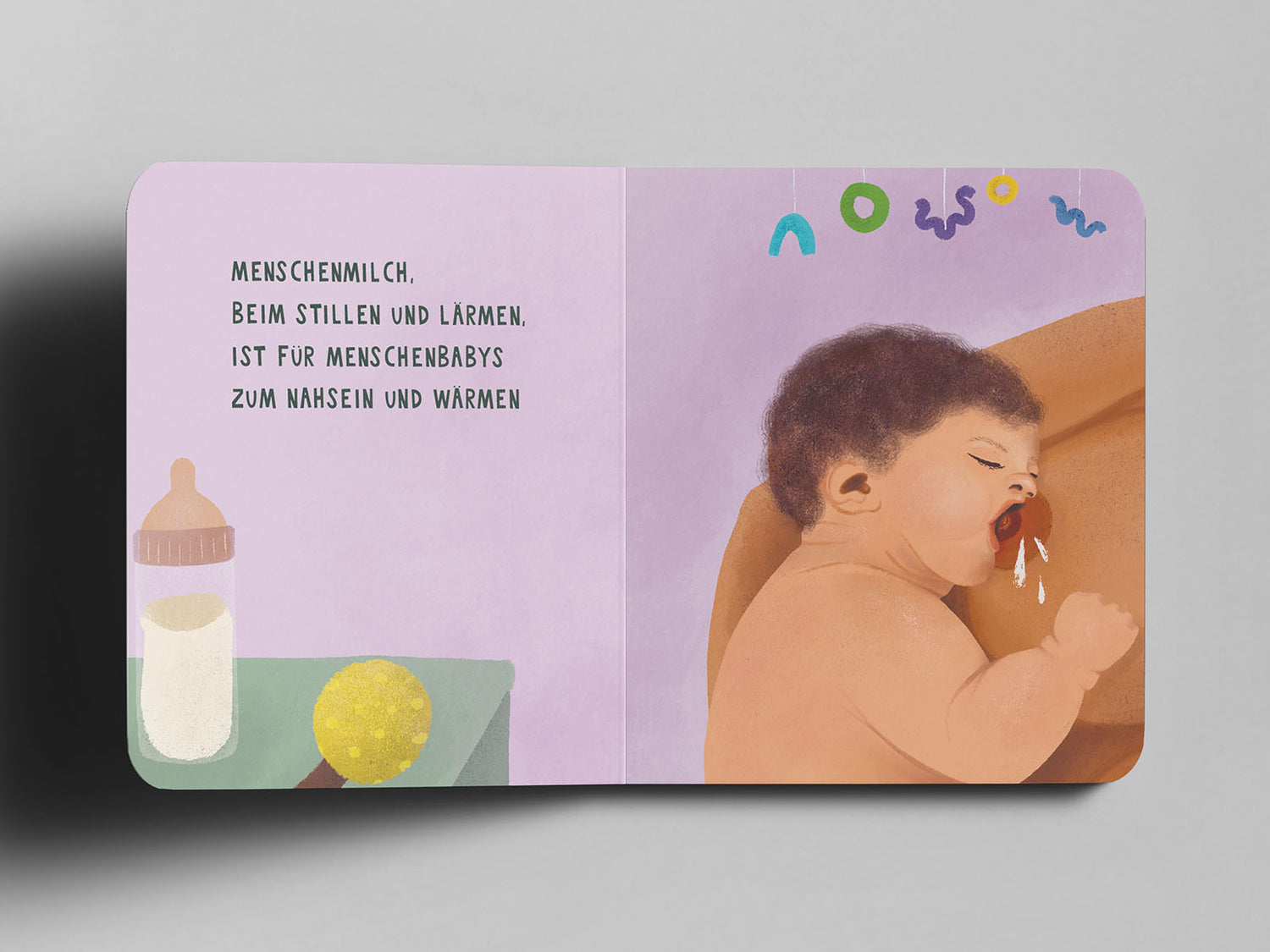 Aufgeschlagenes Pappbuch mit einer Illustration eines stillenden Babys mit lockigem dunklem Haar, das an der Brust der Mutter trinkt. Seine kleine Hand ruht auf der Haut. Der Hintergrund ist in sanftem Lila gehalten. Oben hängt ein Mobile mit bunten Formen. Links im Bild stehen eine Babyflasche mit Milch und eine gelbe Rassel auf einem Tisch. Auf der linken Seite steht in schwarzer Schrift: ‚Menschenmilch, beim Stillen und Lärmen, ist für Menschenbabys zum Nahsein und Wärmen‘.